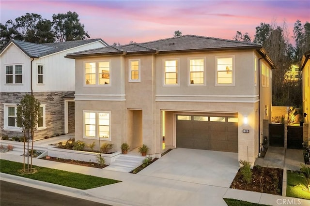 view of front facade with an attached garage, stone siding, concrete driveway, and stucco siding