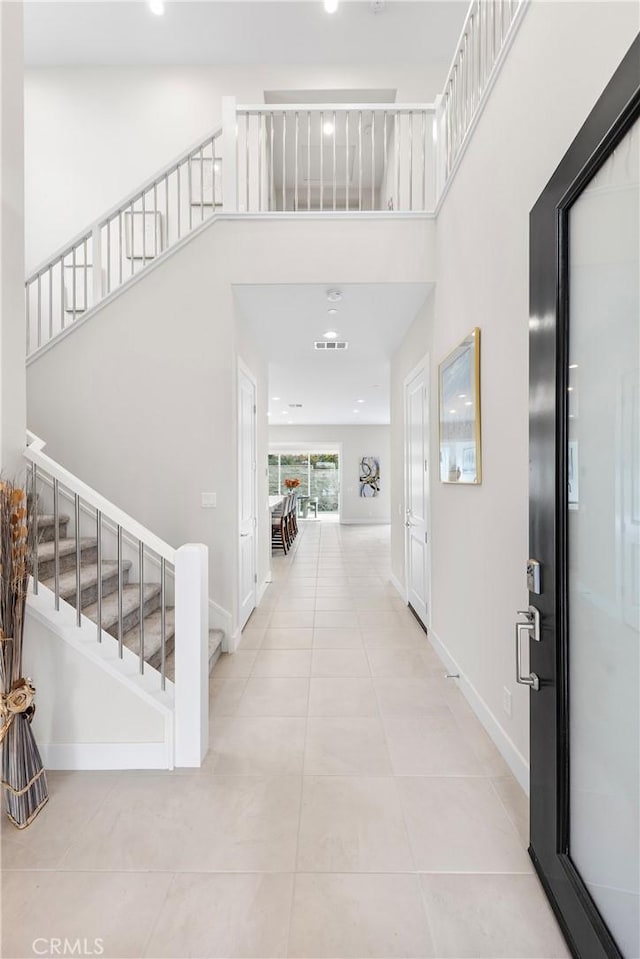 interior space with light tile patterned flooring, stairway, and baseboards