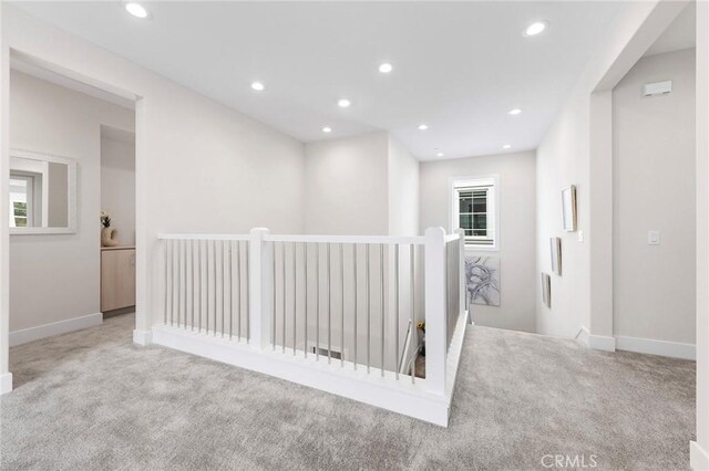 hallway featuring baseboards, carpet flooring, an upstairs landing, and recessed lighting