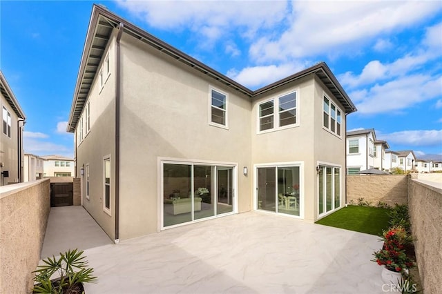 rear view of house featuring a residential view, a patio area, a fenced backyard, and stucco siding