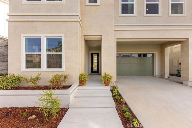 doorway to property featuring driveway, an attached garage, and stucco siding