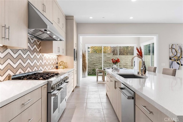 kitchen featuring light tile patterned floors, a breakfast bar area, appliances with stainless steel finishes, decorative backsplash, and sink