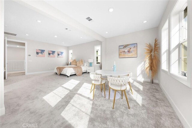 carpeted dining area with plenty of natural light and beamed ceiling