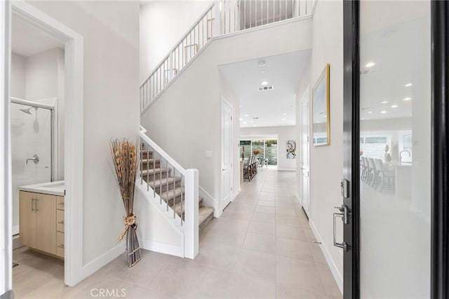 entryway with light tile patterned floors, baseboards, stairs, and visible vents