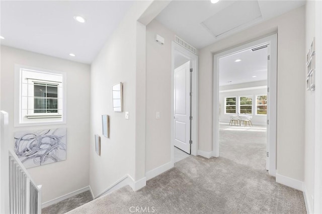 hallway featuring attic access, baseboards, carpet flooring, and recessed lighting