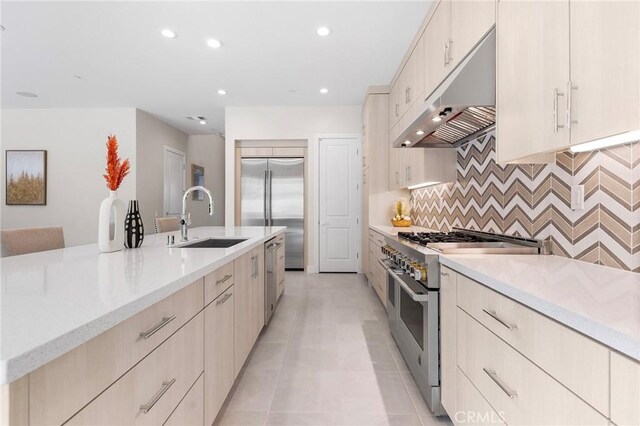 kitchen featuring sink, backsplash, light stone counters, light tile patterned floors, and high quality appliances