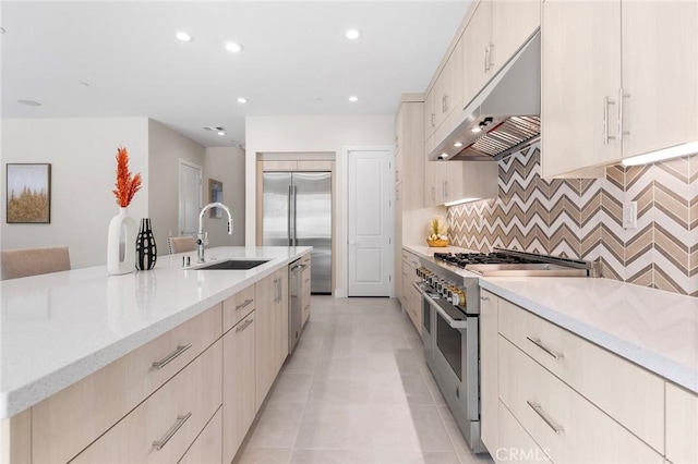 kitchen featuring tasteful backsplash, recessed lighting, a sink, high quality appliances, and under cabinet range hood