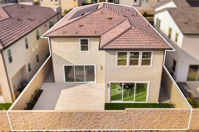 rear view of house with a patio area, fence, and stucco siding