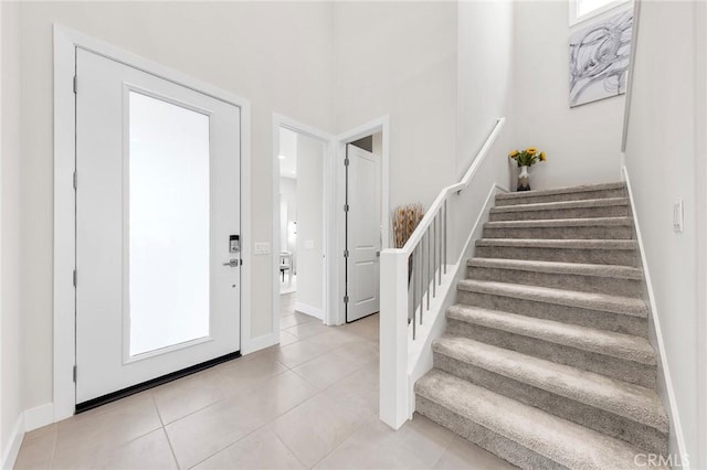 entrance foyer with light tile patterned flooring, baseboards, and stairs