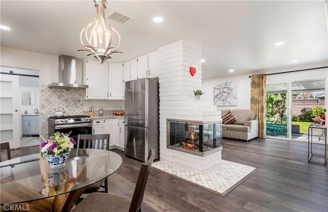 kitchen featuring pendant lighting, white cabinets, appliances with stainless steel finishes, wall chimney exhaust hood, and a barn door