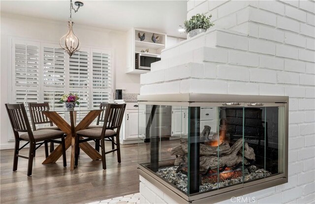 kitchen with wood-type flooring, white cabinetry, pendant lighting, and crown molding