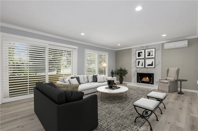 living room featuring an AC wall unit, light wood-type flooring, crown molding, and a fireplace