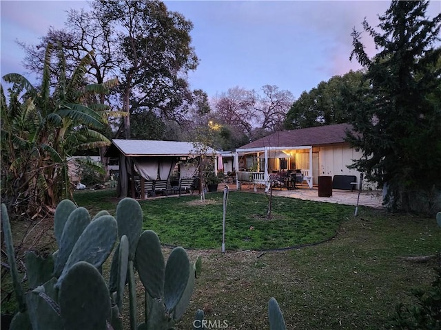 back house at dusk featuring a yard