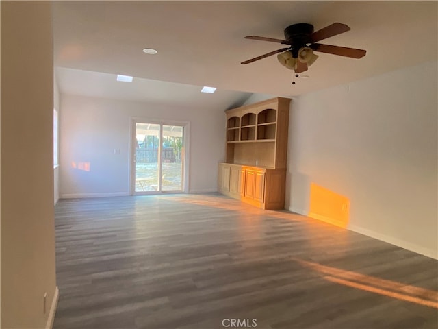 unfurnished living room featuring dark wood-type flooring and ceiling fan