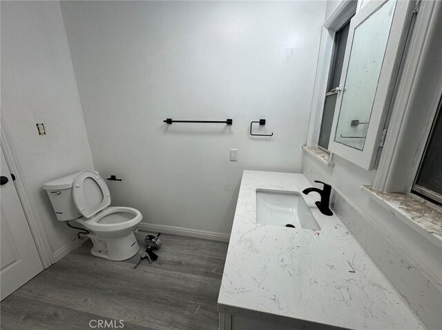 bathroom with toilet, vanity, and hardwood / wood-style flooring