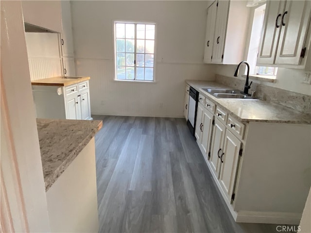 kitchen with dark hardwood / wood-style floors, dishwasher, white cabinets, light stone counters, and sink