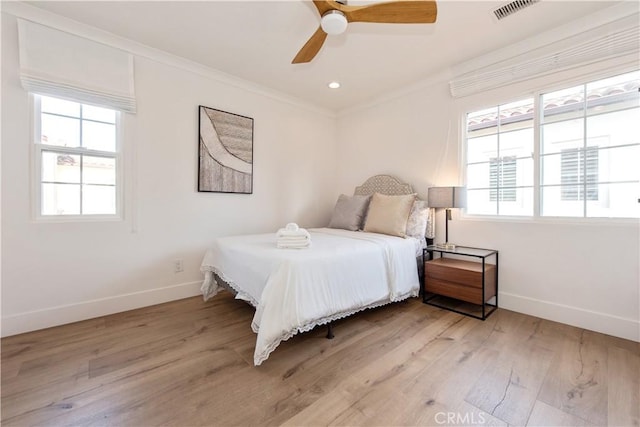 bedroom with ceiling fan, multiple windows, light hardwood / wood-style flooring, and crown molding