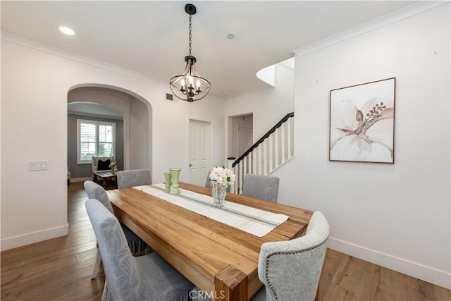 dining space with a notable chandelier, ornamental molding, and hardwood / wood-style floors