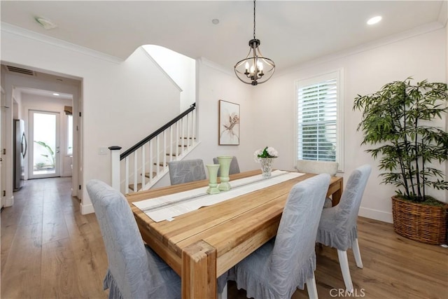 dining space with a notable chandelier, crown molding, and hardwood / wood-style floors