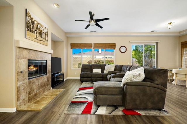 living room featuring ceiling fan, dark hardwood / wood-style flooring, and a tiled fireplace