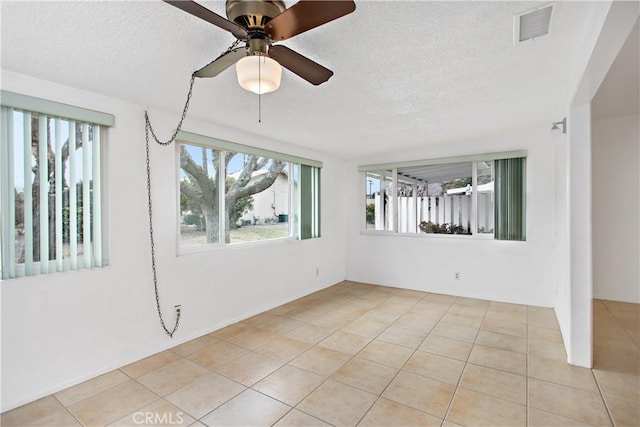 empty room featuring ceiling fan, plenty of natural light, and light tile patterned floors