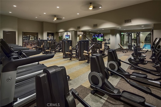 exercise room with ceiling fan, light carpet, and a high ceiling