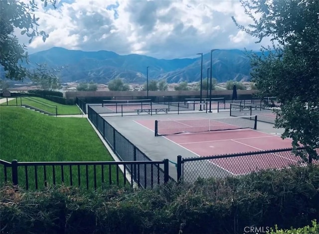 view of tennis court featuring a mountain view and a yard