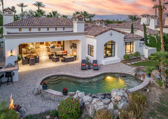 back house at dusk featuring an outdoor living space and a patio area