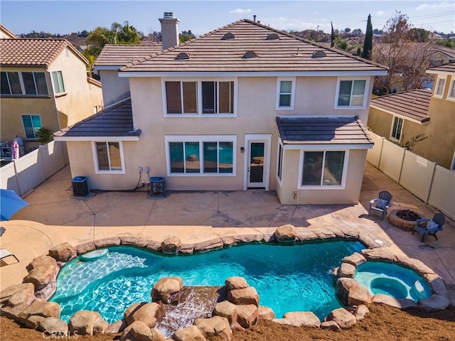 rear view of property with a patio, a pool with hot tub, central AC unit, and a fire pit