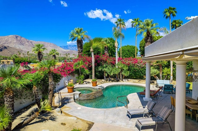 view of swimming pool with a patio area, a mountain view, and an in ground hot tub