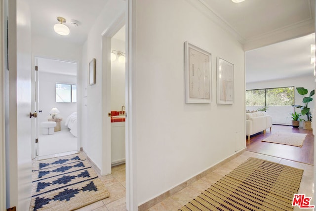 hallway with sink, light tile patterned floors, and crown molding