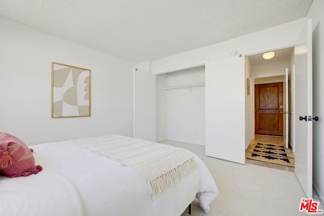 bedroom with light carpet, a closet, and a textured ceiling