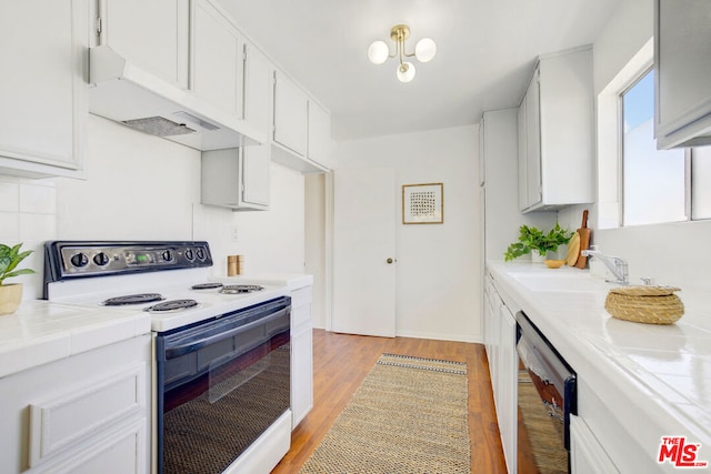 kitchen with exhaust hood, dishwasher, tile countertops, electric range, and white cabinetry