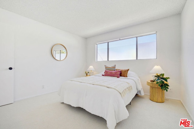 bedroom featuring a textured ceiling and light carpet