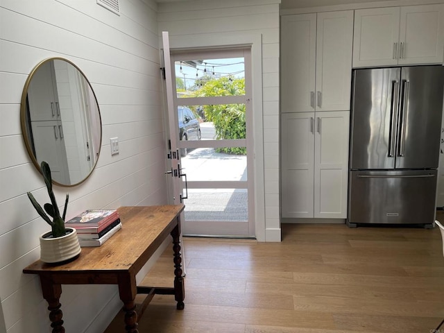 doorway to outside featuring light hardwood / wood-style flooring and wooden walls