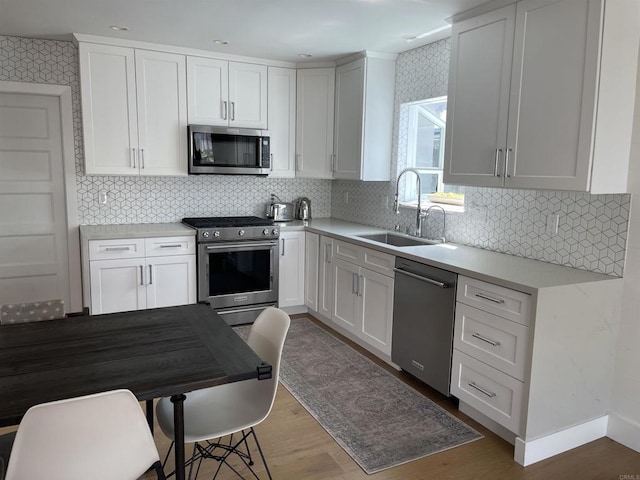 kitchen with hardwood / wood-style flooring, sink, white cabinetry, and stainless steel appliances