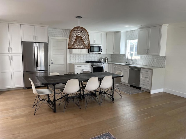 kitchen featuring white cabinets, light hardwood / wood-style flooring, high end appliances, and pendant lighting