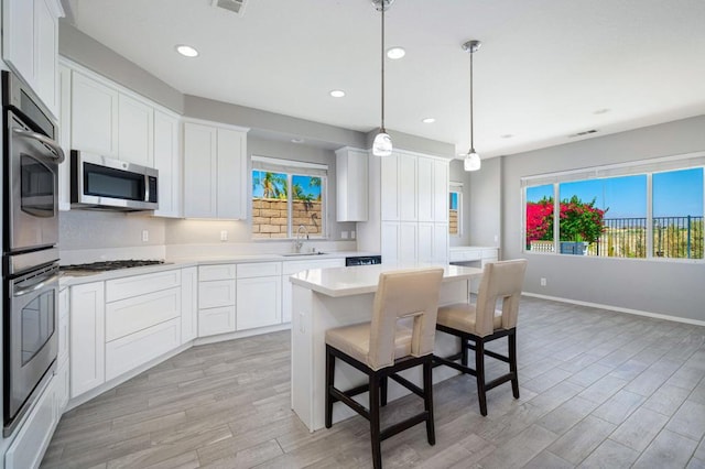 kitchen with decorative light fixtures, sink, white cabinetry, and stainless steel appliances