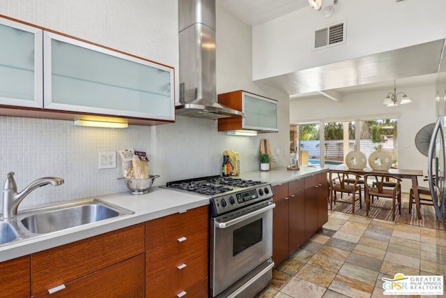 kitchen with high end stainless steel range oven, backsplash, decorative light fixtures, wall chimney exhaust hood, and sink