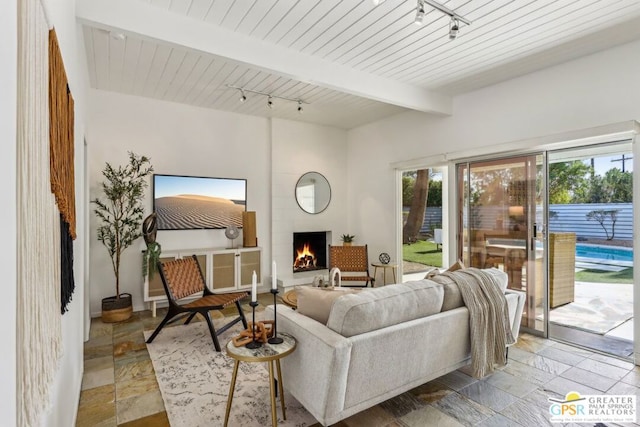 living room with track lighting, wood ceiling, a fireplace, and beamed ceiling