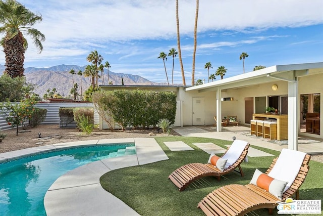 view of swimming pool with a bar, a mountain view, and a patio