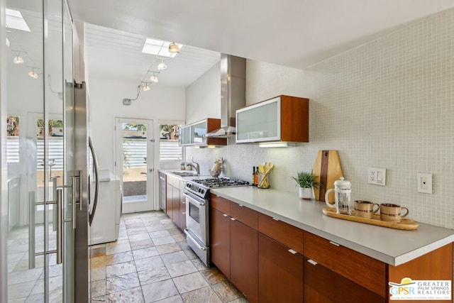 kitchen with a skylight, decorative backsplash, sink, stainless steel range with gas stovetop, and range hood