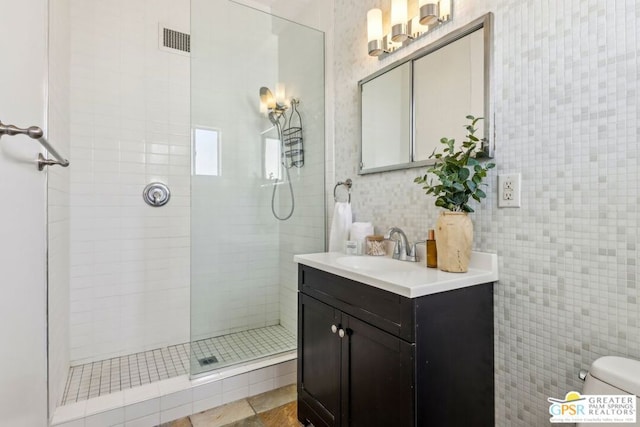 bathroom with vanity, toilet, tile walls, and tiled shower