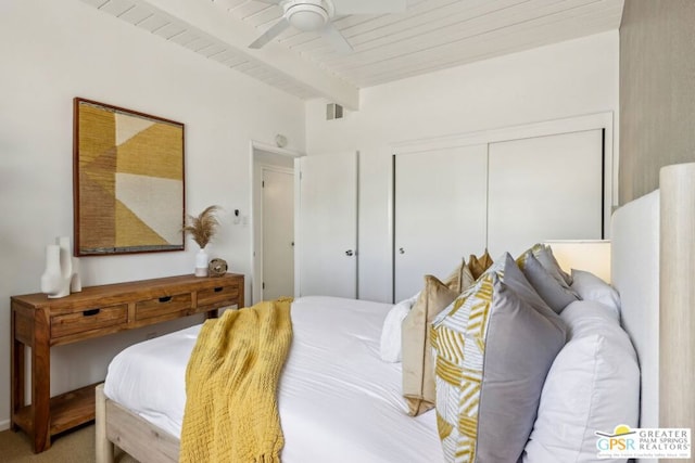 bedroom featuring ceiling fan, wooden ceiling, carpet floors, a closet, and beamed ceiling