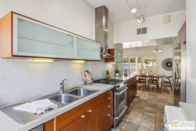 kitchen featuring appliances with stainless steel finishes, wall chimney exhaust hood, decorative backsplash, and sink