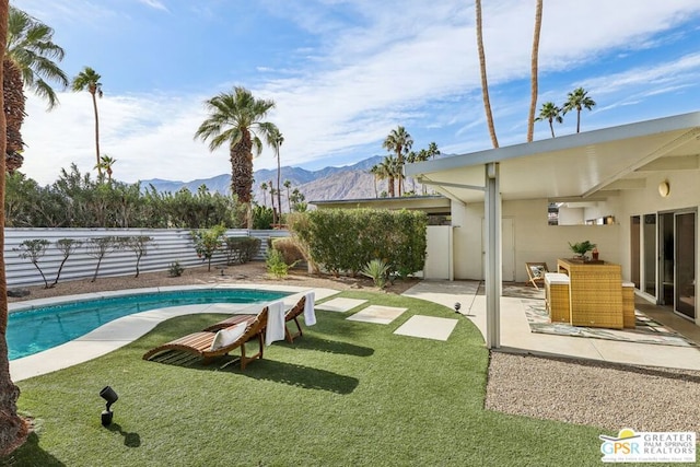 view of pool with a patio area, a mountain view, and a yard