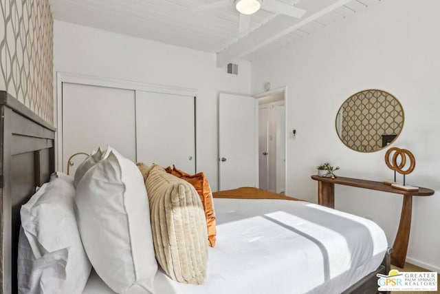 bedroom with ceiling fan, a closet, wood ceiling, and beamed ceiling