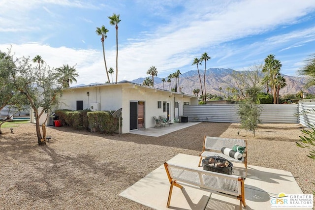 rear view of property with a fire pit, central AC unit, a mountain view, and a patio