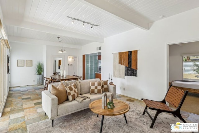 living room with rail lighting, beam ceiling, and a notable chandelier