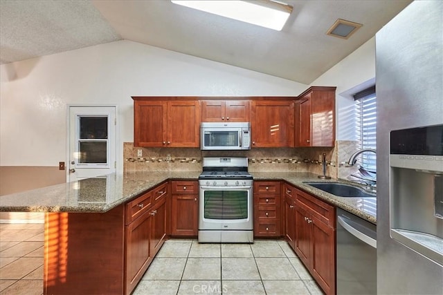 kitchen with vaulted ceiling, kitchen peninsula, sink, light tile patterned flooring, and stainless steel appliances